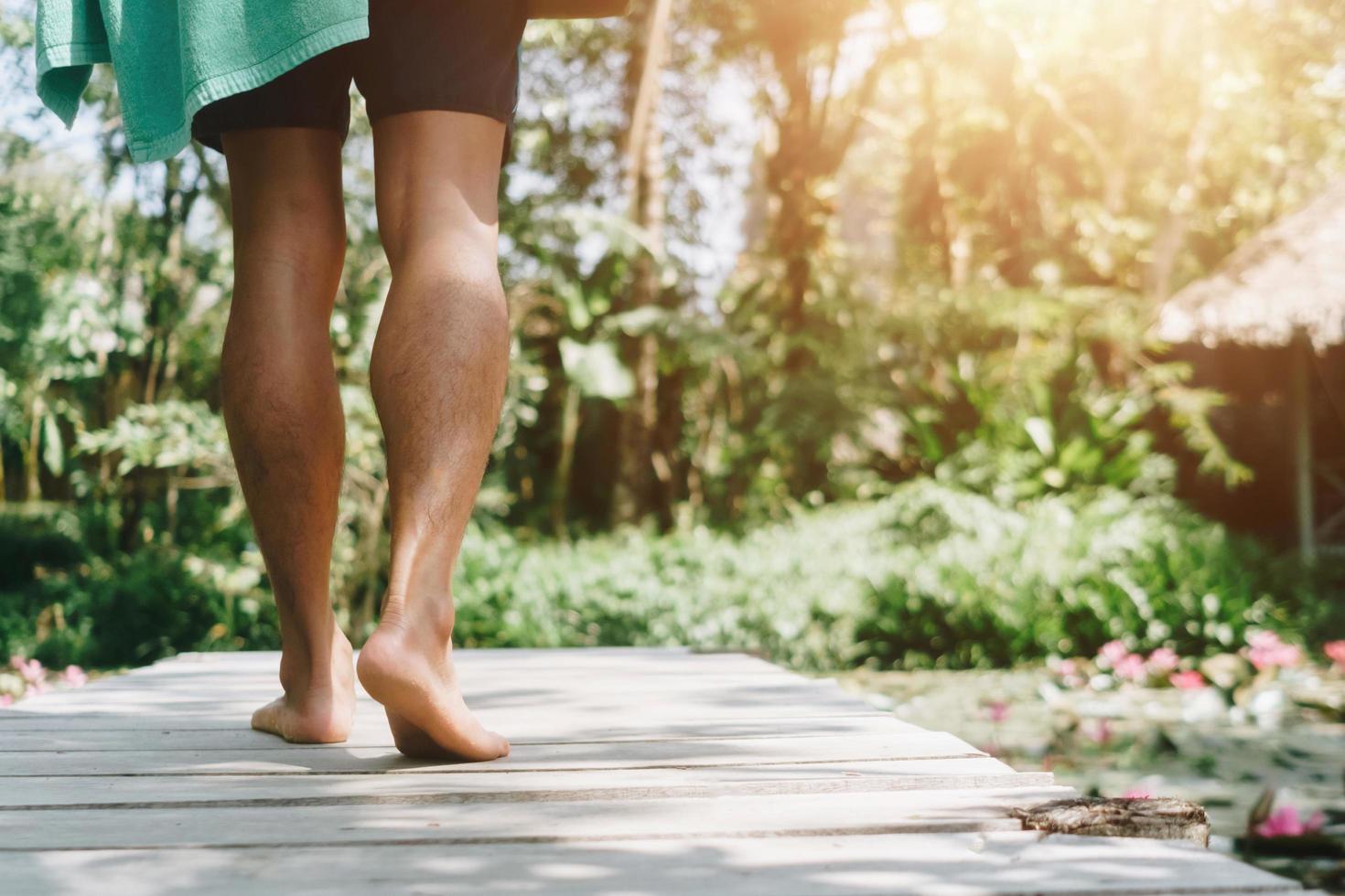 A person walking on a small wooden walkway with a sunlight flare in a tropical location photo