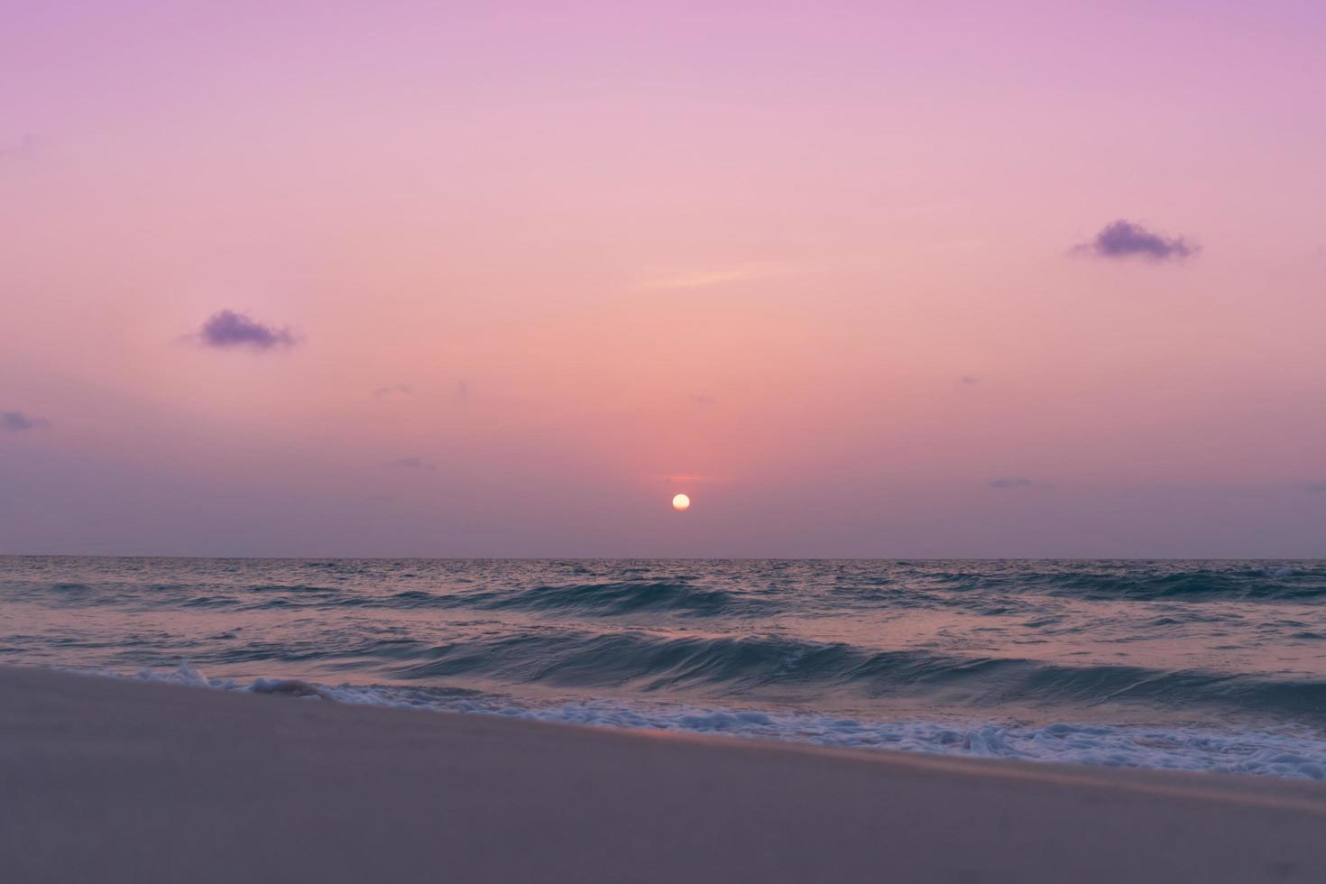 Coloridas olas del mar durante un amanecer o atardecer rosa con el sol de fondo foto