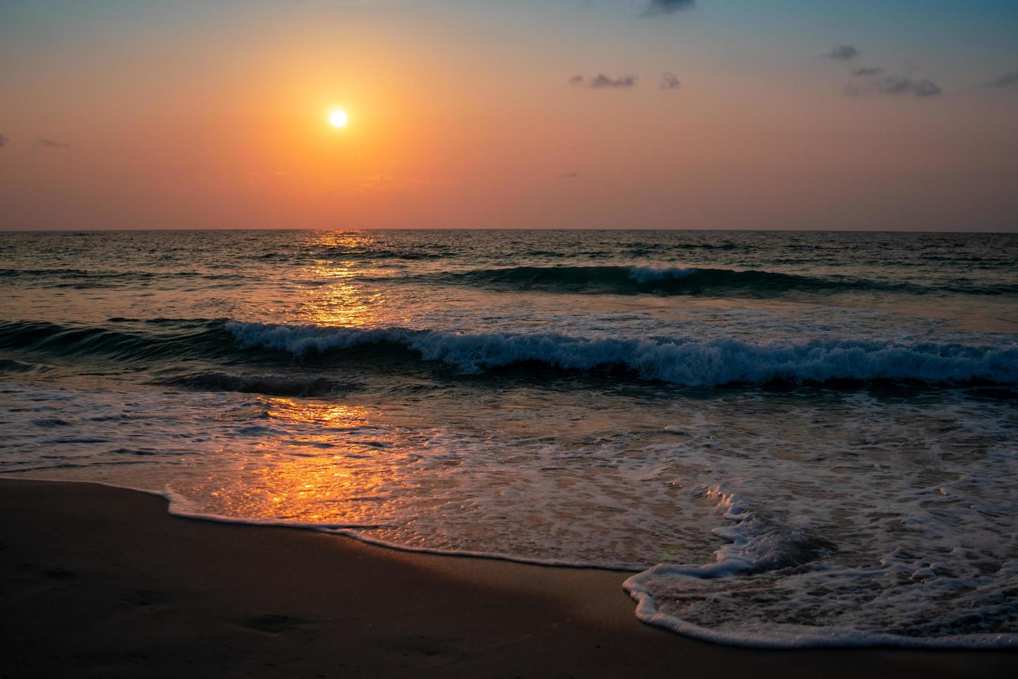 Colorful ocean sea waves during a sunrise or sunset with the sun in the background photo