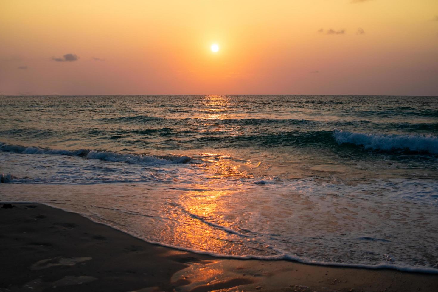Coloridas olas del mar durante un amanecer o atardecer con el sol de fondo foto