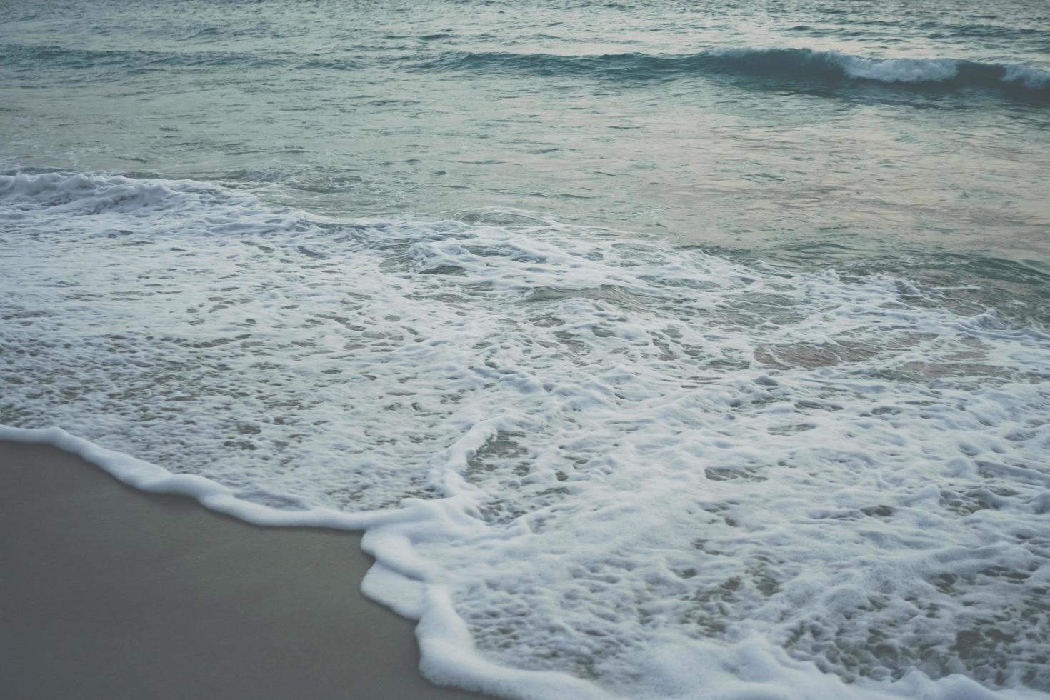 Tono de desvanecimiento vintage de las olas del mar en la playa durante el verano foto