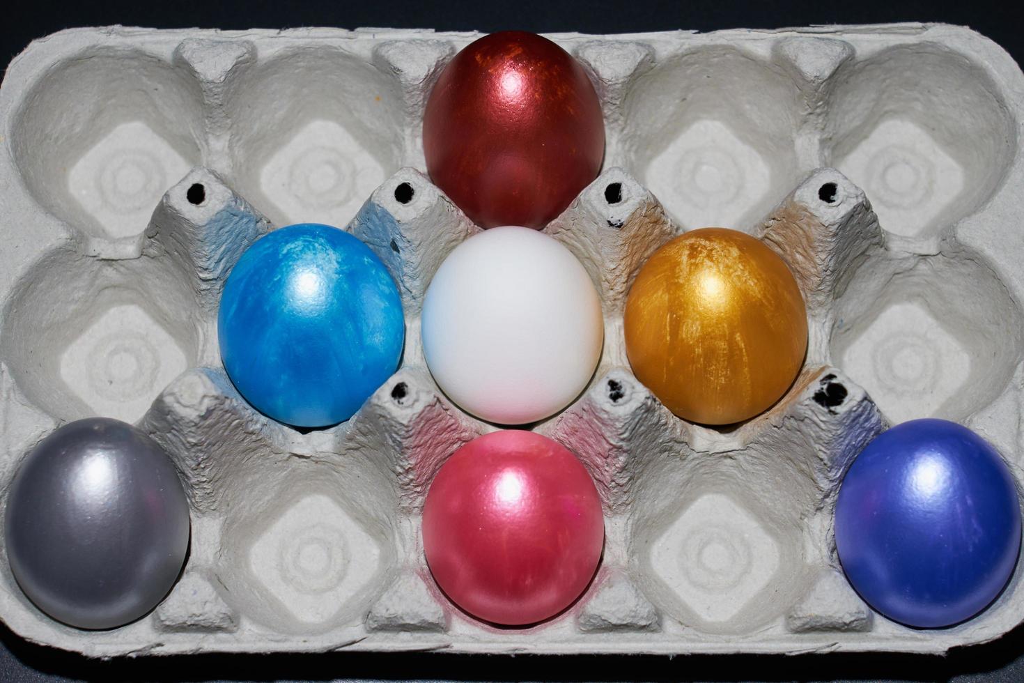 huevos de pascua de color nacarado en un cartón de huevos foto