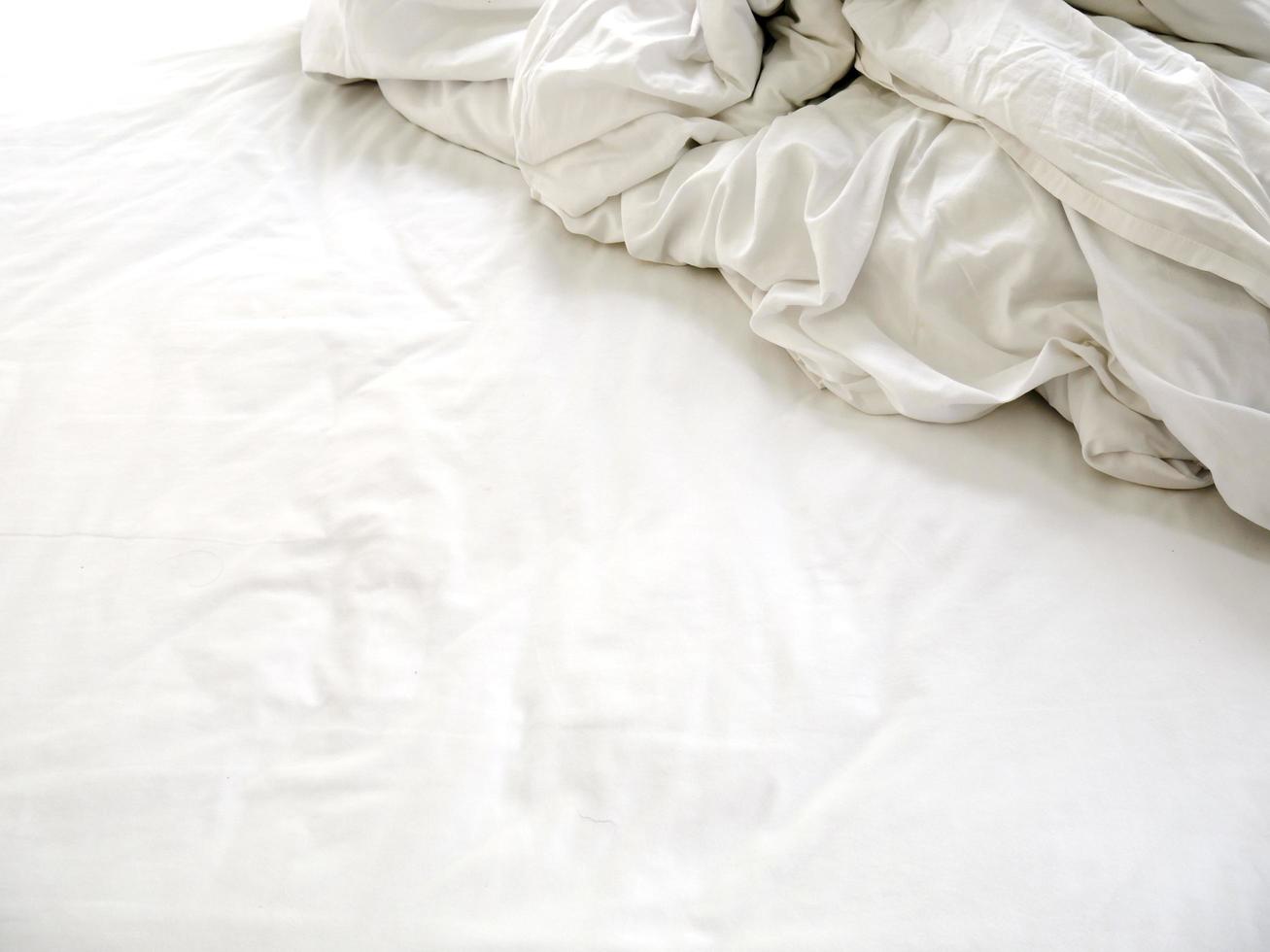 White sheets on an unmade bed photo