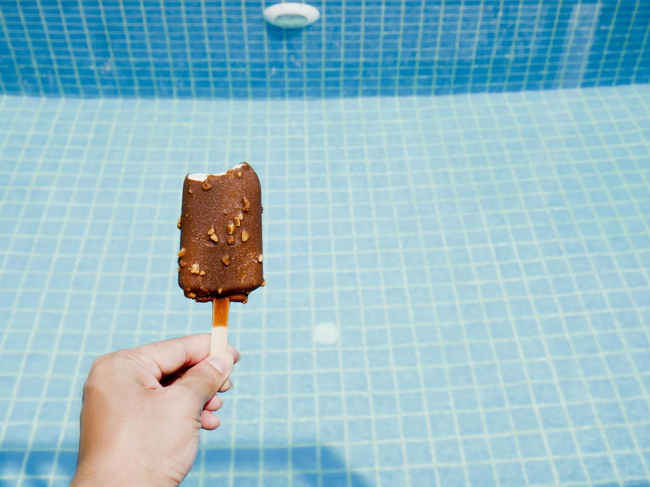 Person holding ice cream by the pool photo