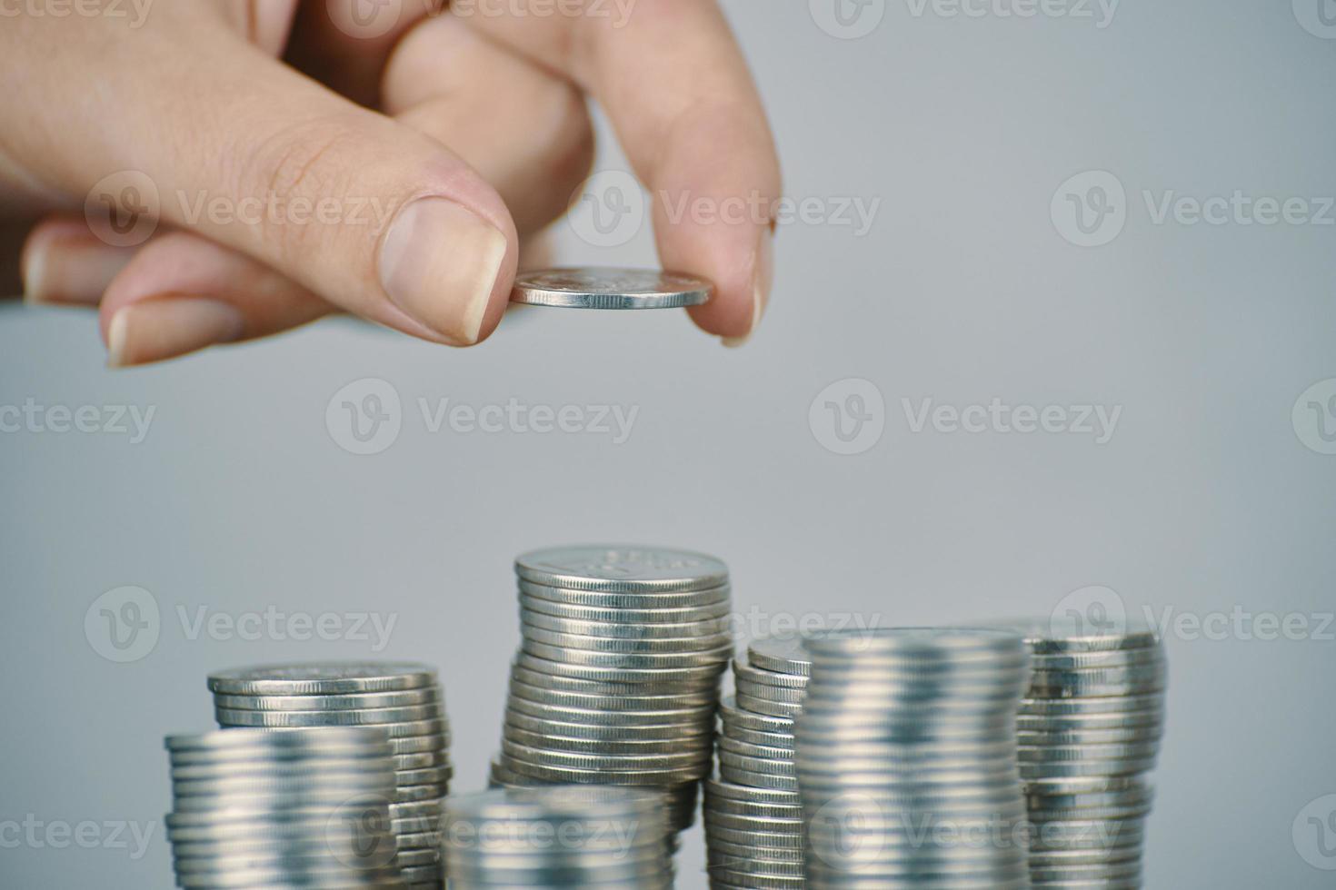 Mano de mujer poniendo monedas de plata para apilar foto