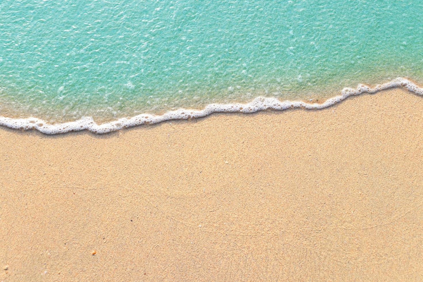 Soft waves with foam of blue ocean on the sandy beach photo