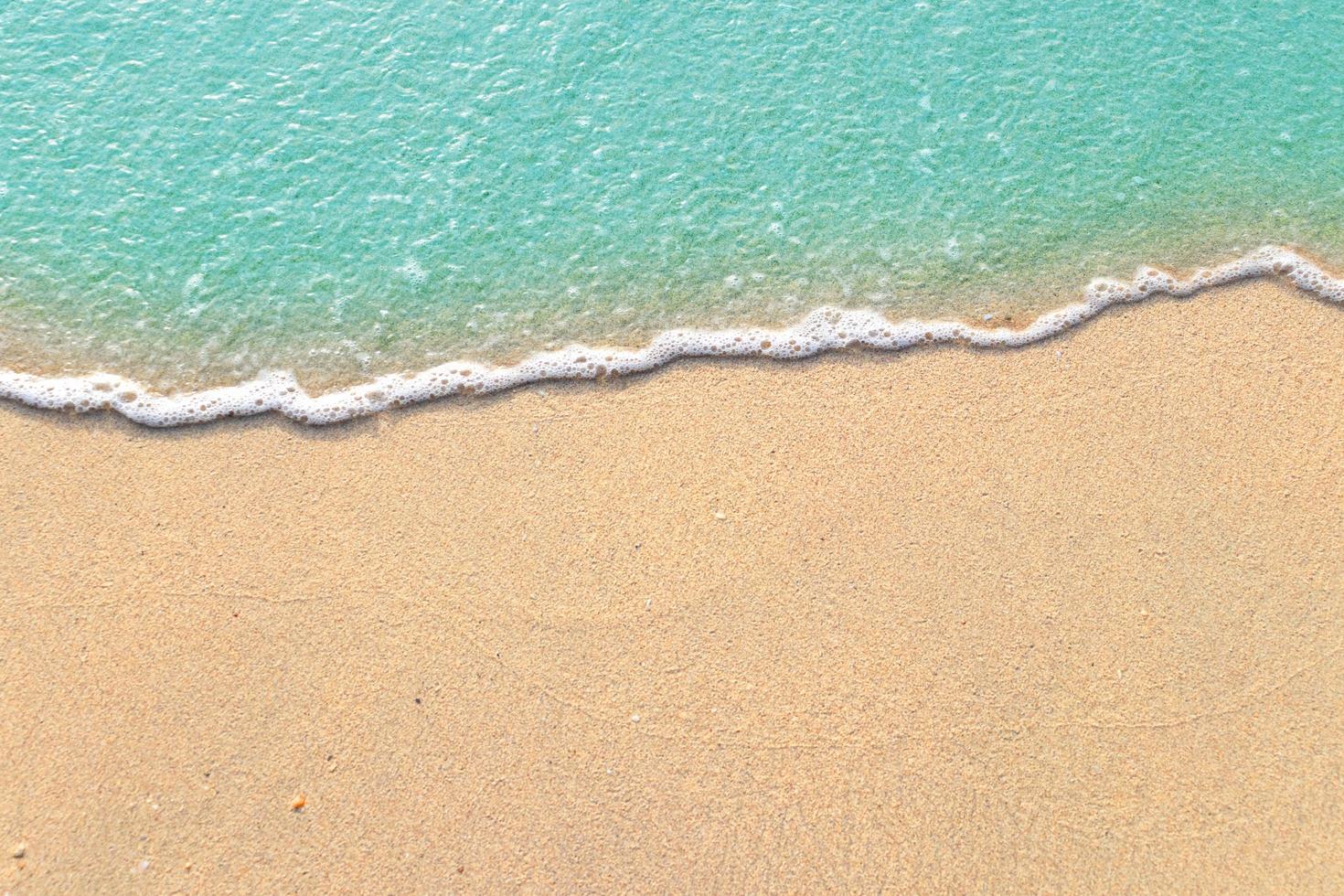 Soft waves with foam of blue ocean on the sandy beach photo