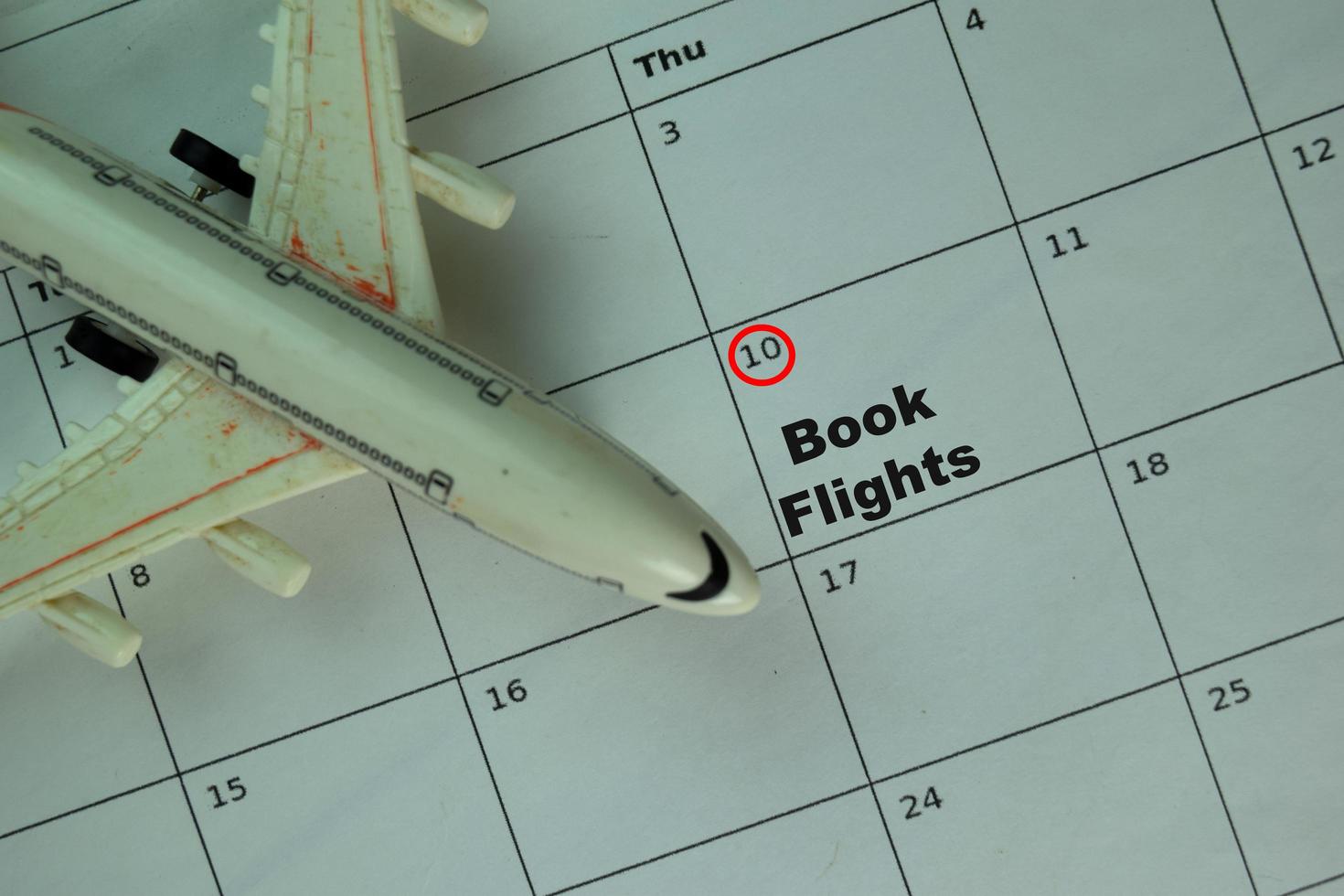 Book flights written on monthly calendar and marked 10th isolated on office desk photo