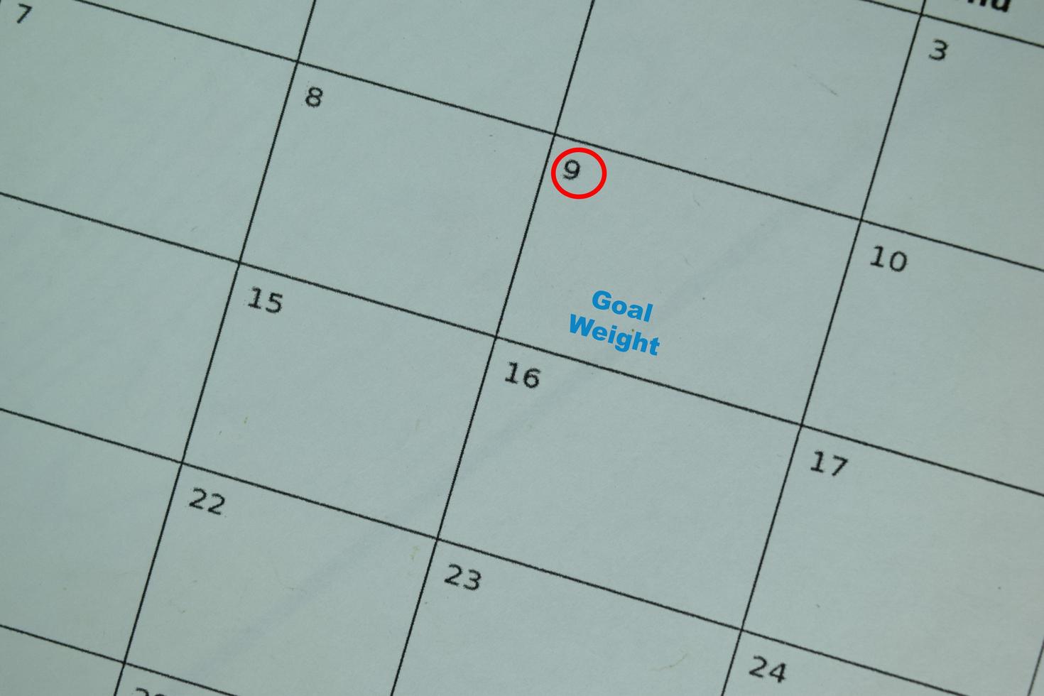Goal weight on monthly calendar and marked 9th isolated on office desk photo