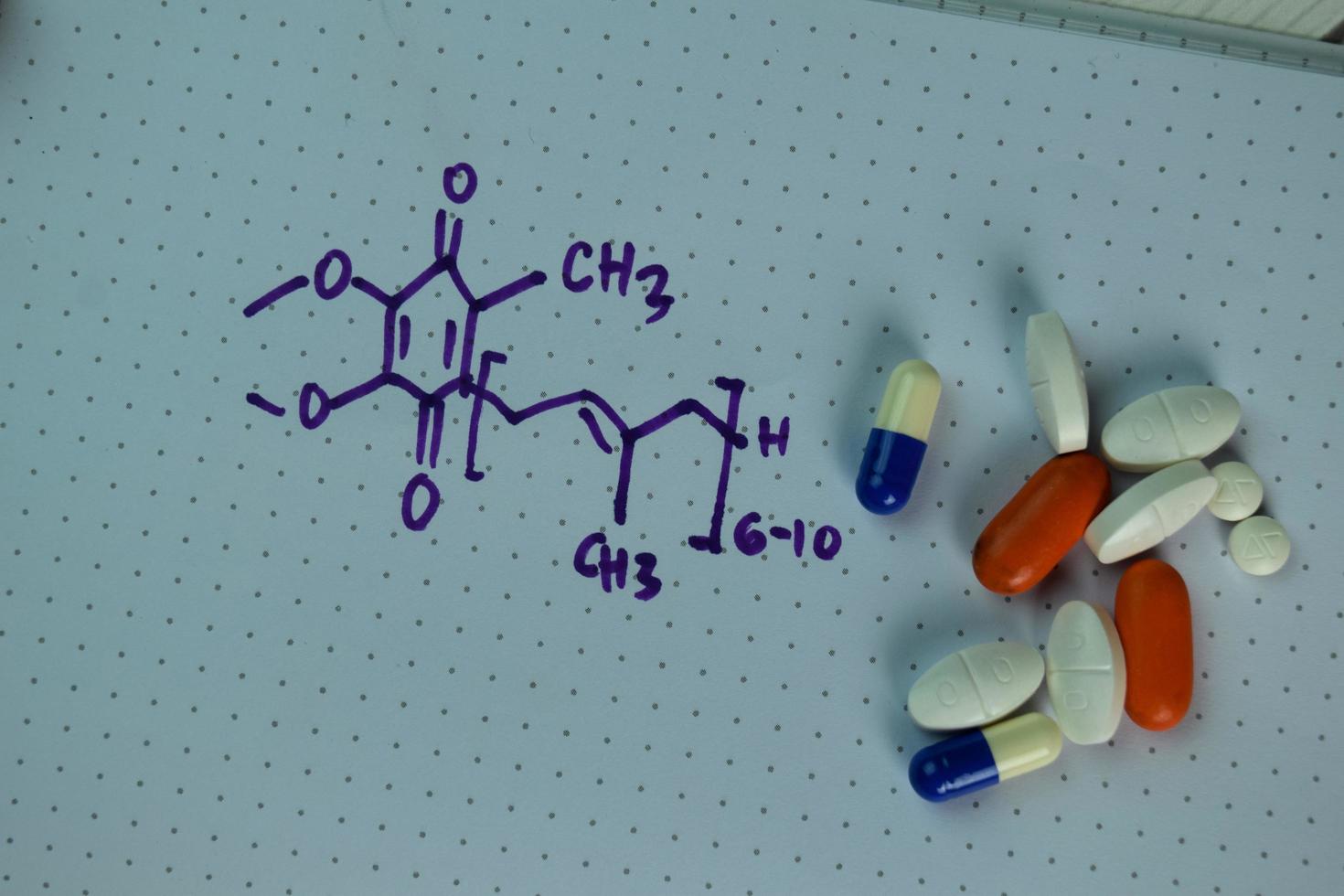 Vitamin coenzyme Q10 with chemical formula written on a book isolated on wooden table photo