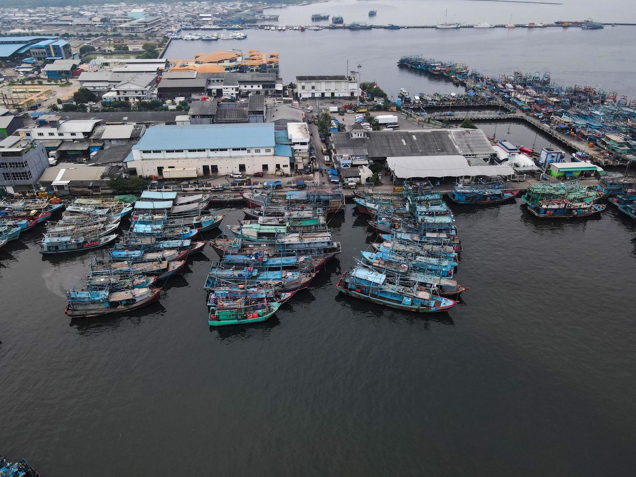 Jakarta, Indonesia 2021- Aerial drone view of Muara Angke beach with wooden boats leaning beside the pier photo