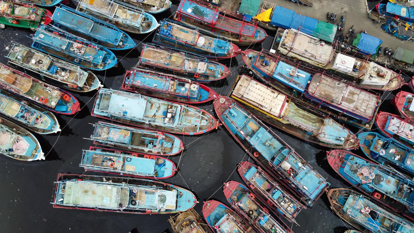 Jakarta, Indonesia 2021- Aerial drone view of Muara Angke beach with wooden boats leaning beside the pier photo