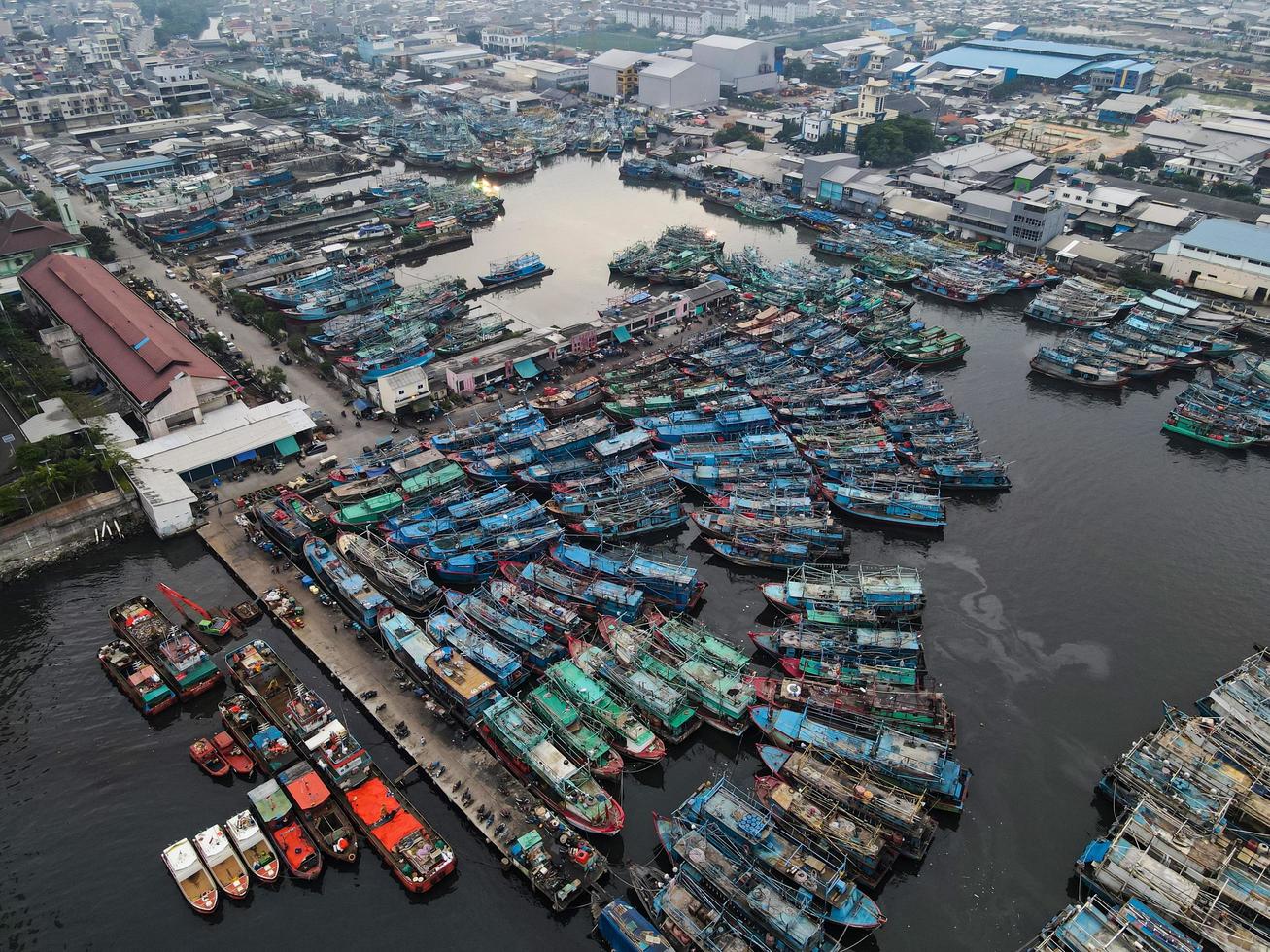 Jakarta, Indonesia 2021- Aerial drone view of Muara Angke beach with wooden boats leaning beside the pier photo