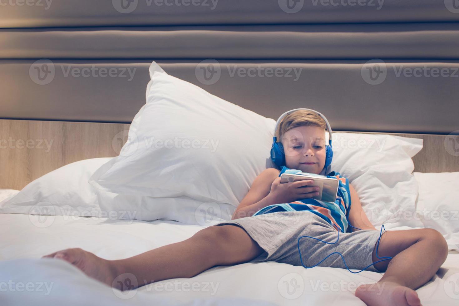 Relaxed boy using smartphone on the bed photo