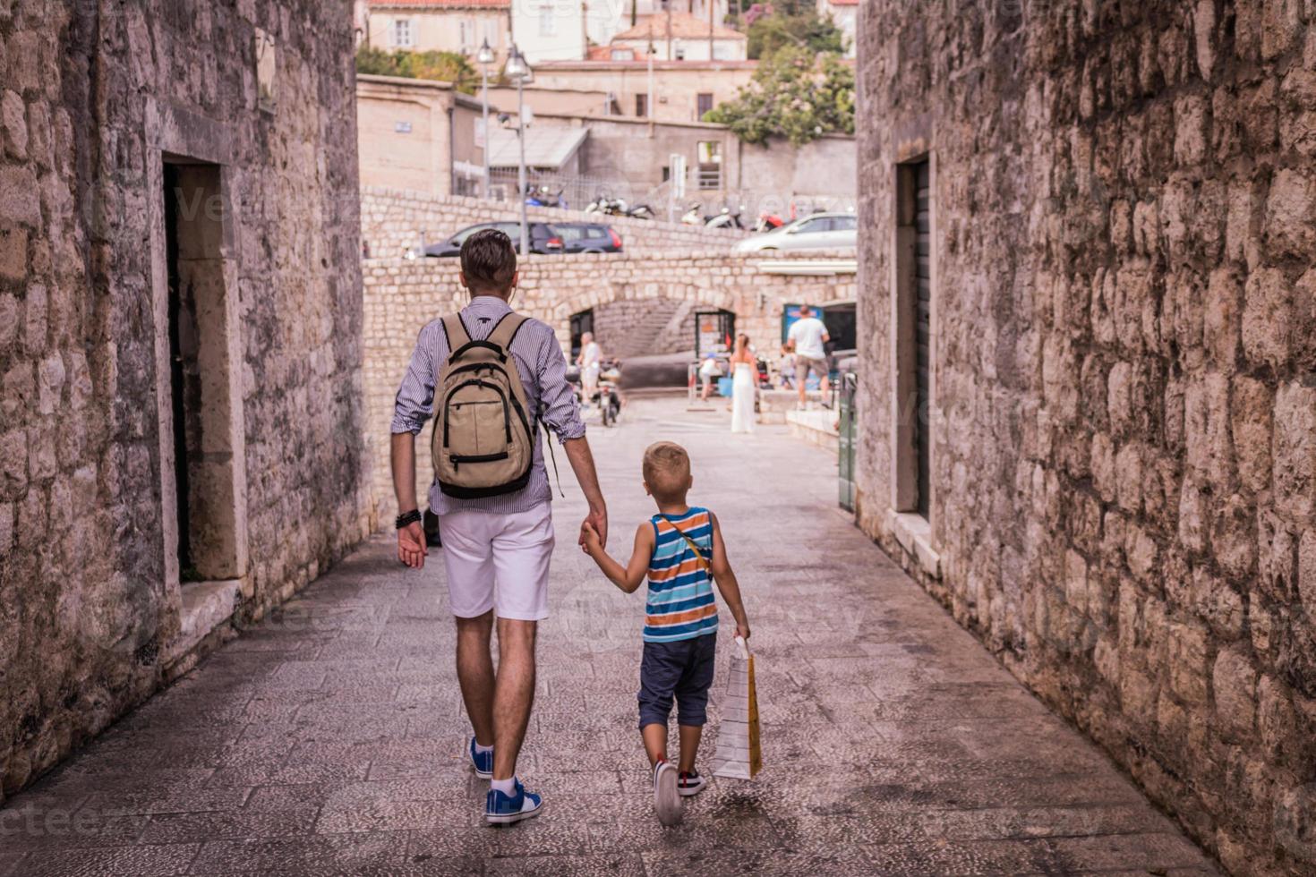 Father and son walking through the city and holding hands photo