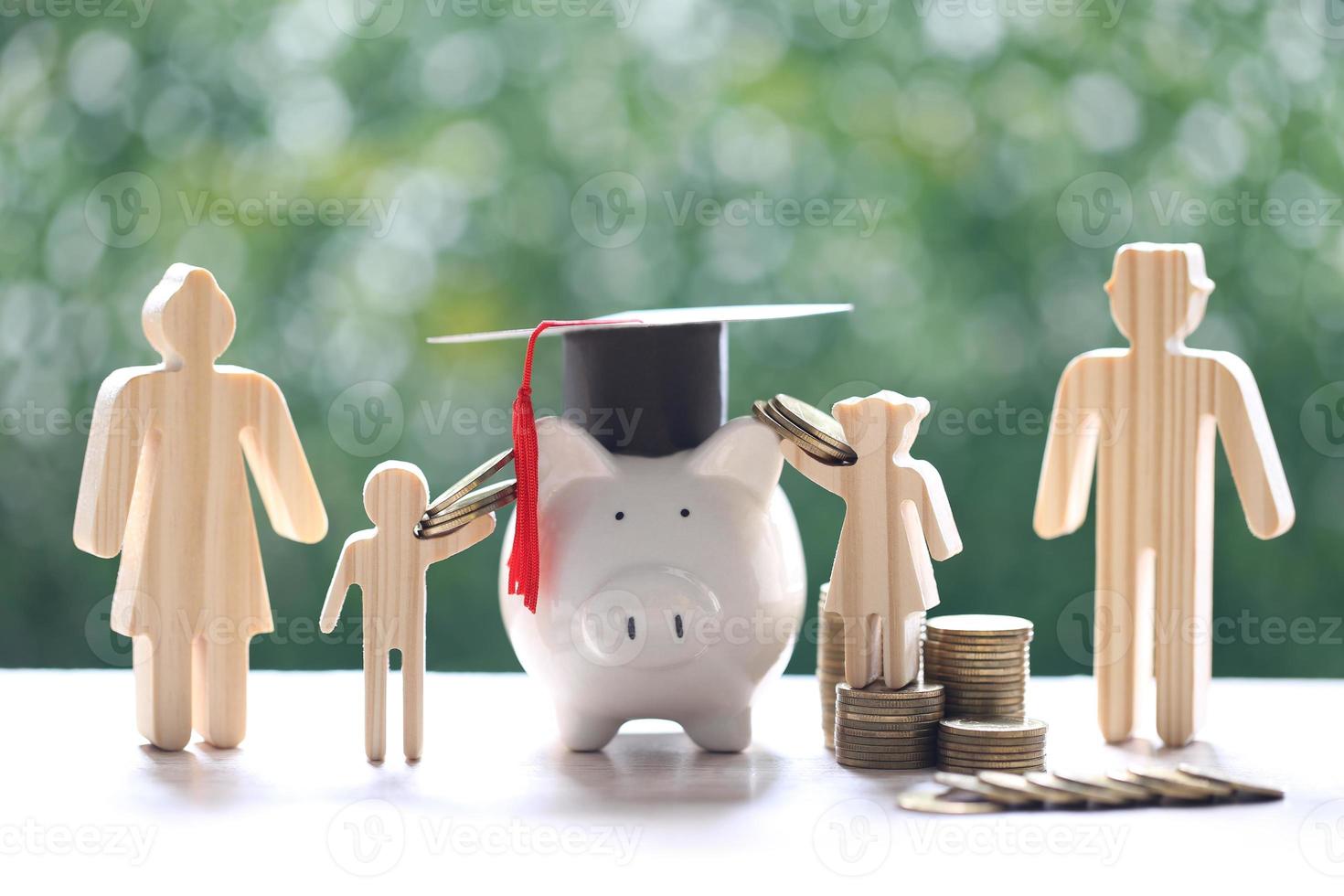 Graduation hat on piggy bank with model family and stack of coins on natural green background photo