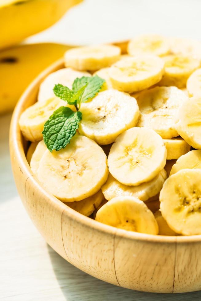 Raw yellow banana slices in wooden bowl photo