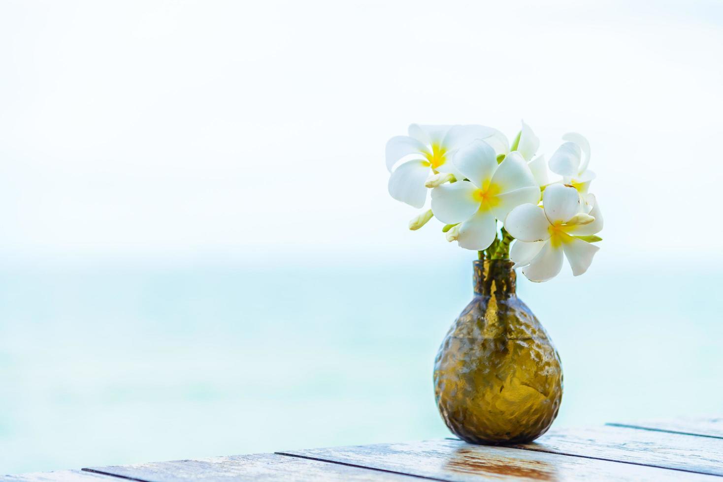 Vase on wooden table with sea background photo