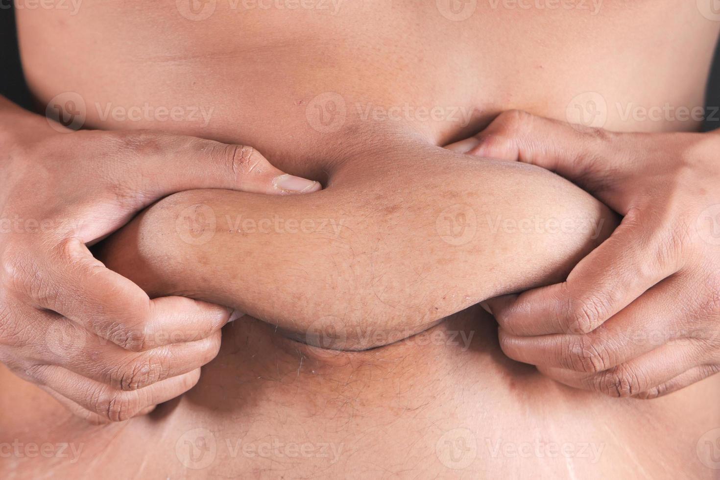 Close up of person holding excess stomach fat photo