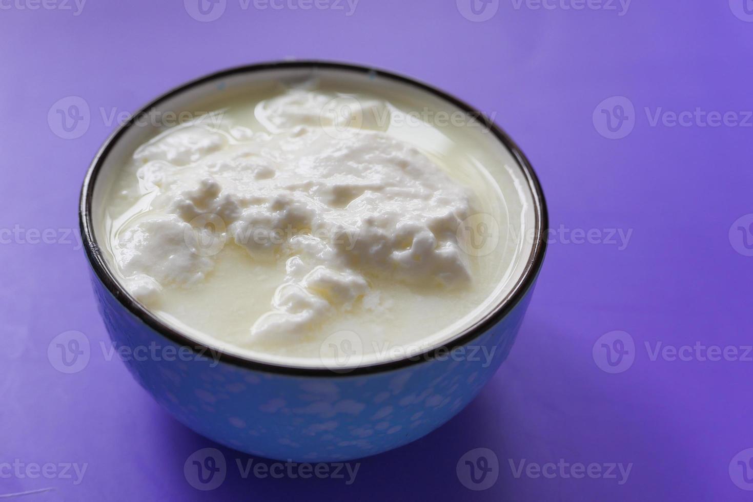 Fresh yogurt in a bowl on purple background photo