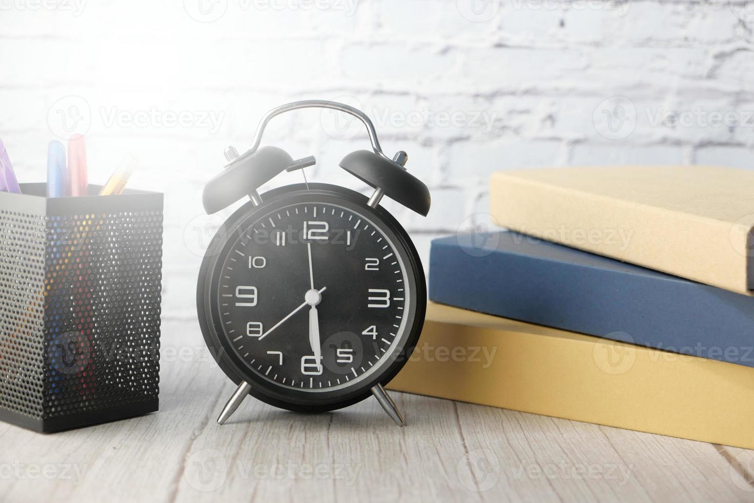 Books and alarm clock on office desk photo