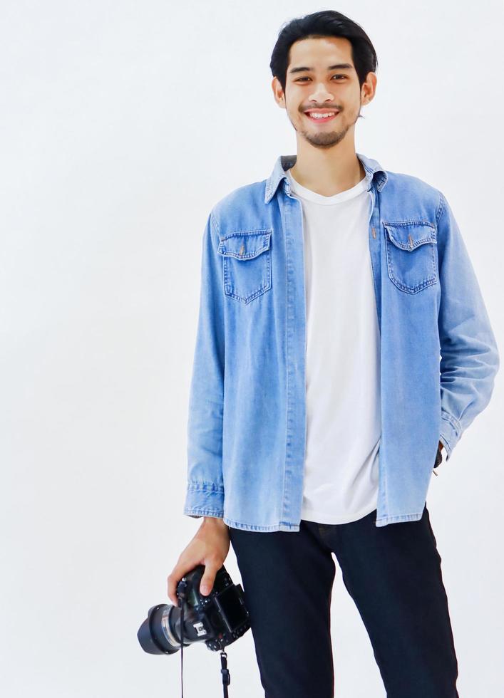 Handsome young photographer standing with a camera on a white background photo