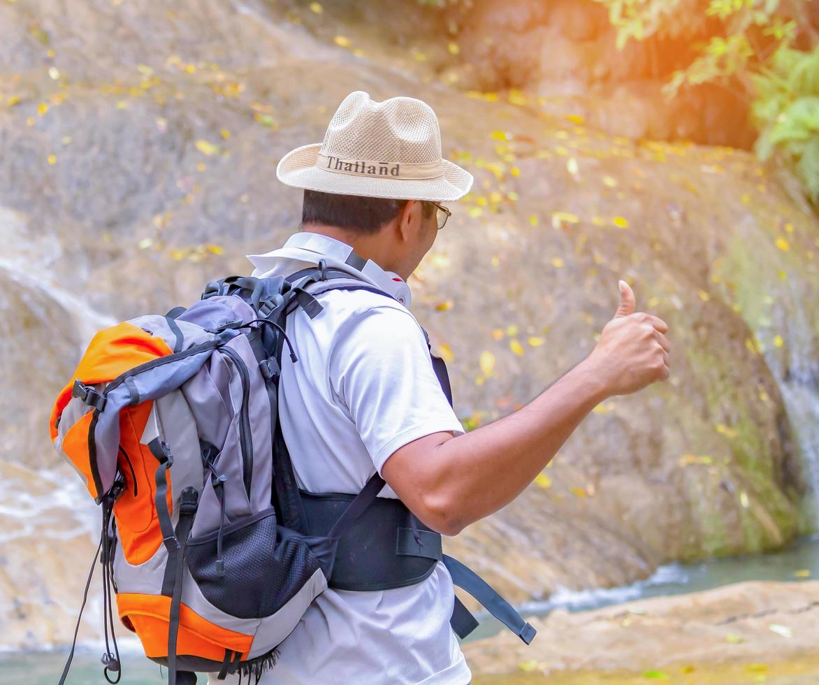 Asian traveler raises hands with pleasure to breathe fresh air while studying nature photo