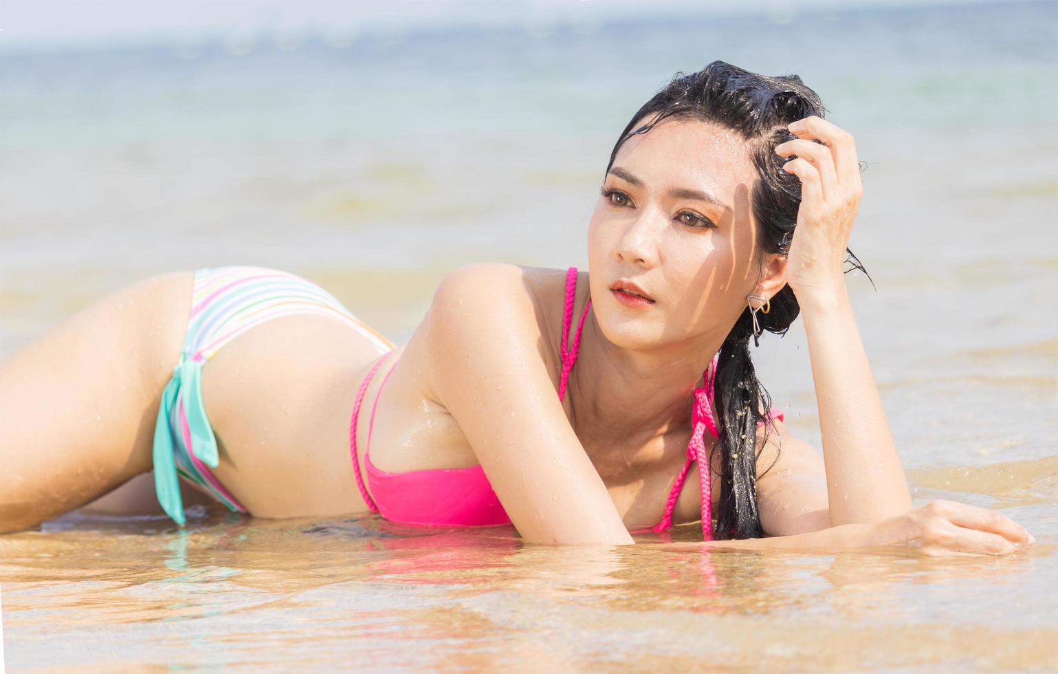 Beautiful Asian woman lounging on the beach happily photo