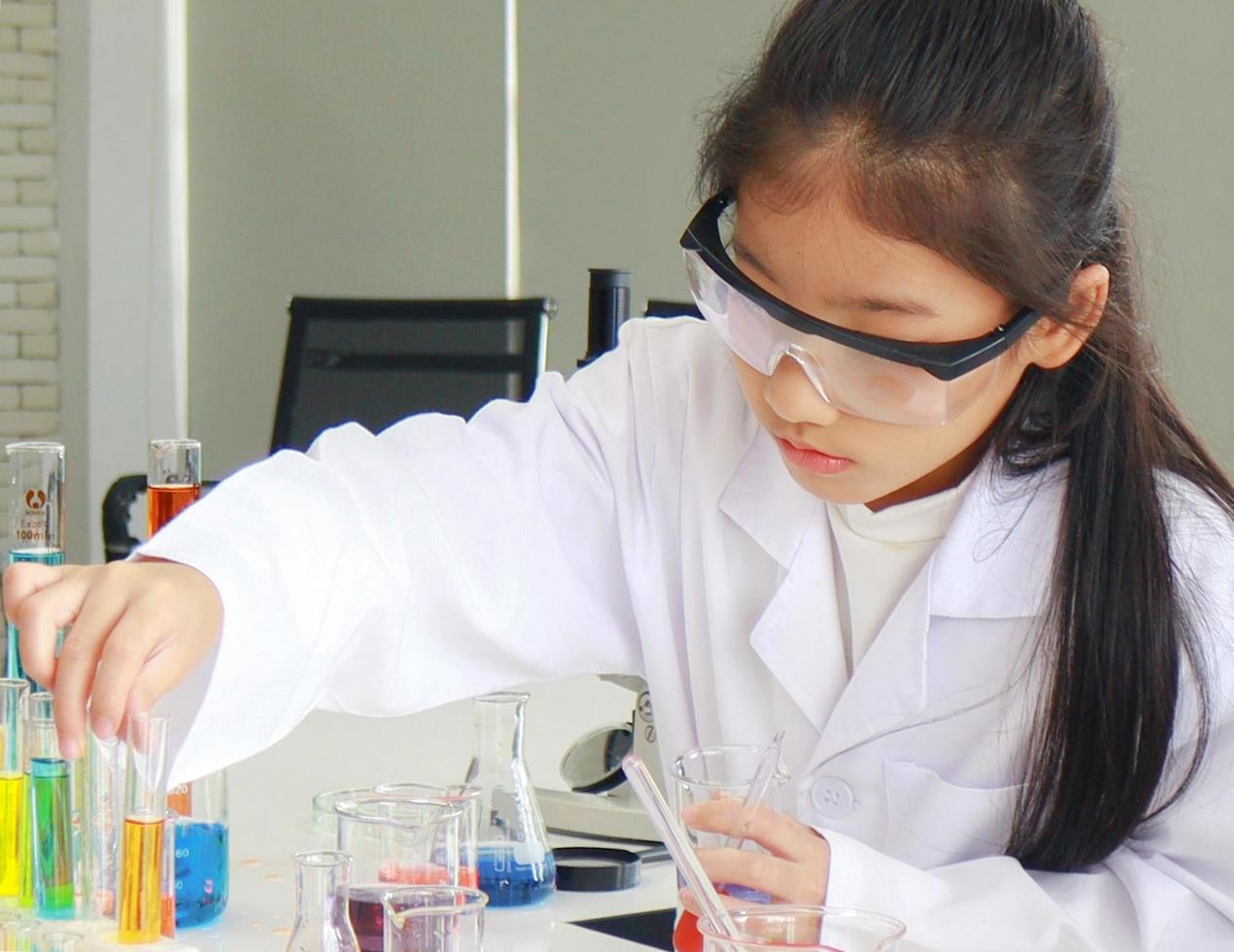 Joven estudiante haciendo experimentos científicos con un tubo químico en un laboratorio foto