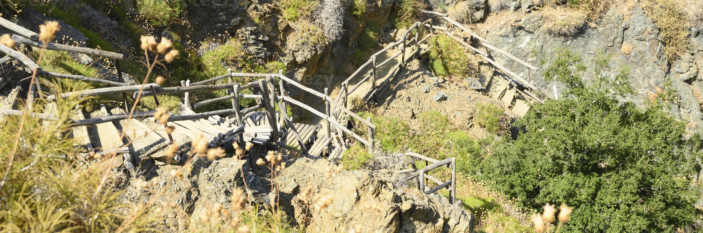 Old homemade wooden staircase that runs over rocks in a mountain gorge photo