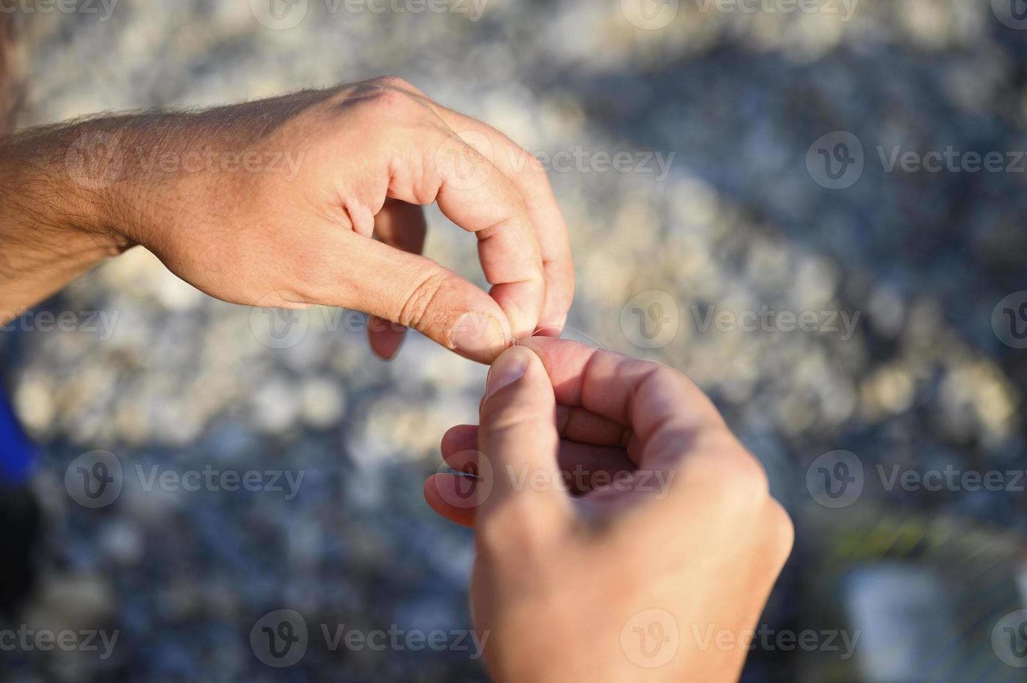 Las manos del hombre atando un hilo de pescar en un anzuelo de pesca foto