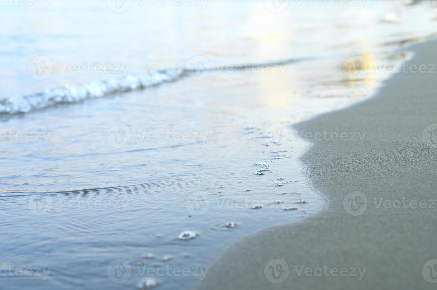 Blurred wave of the sea on the evening sand beach photo