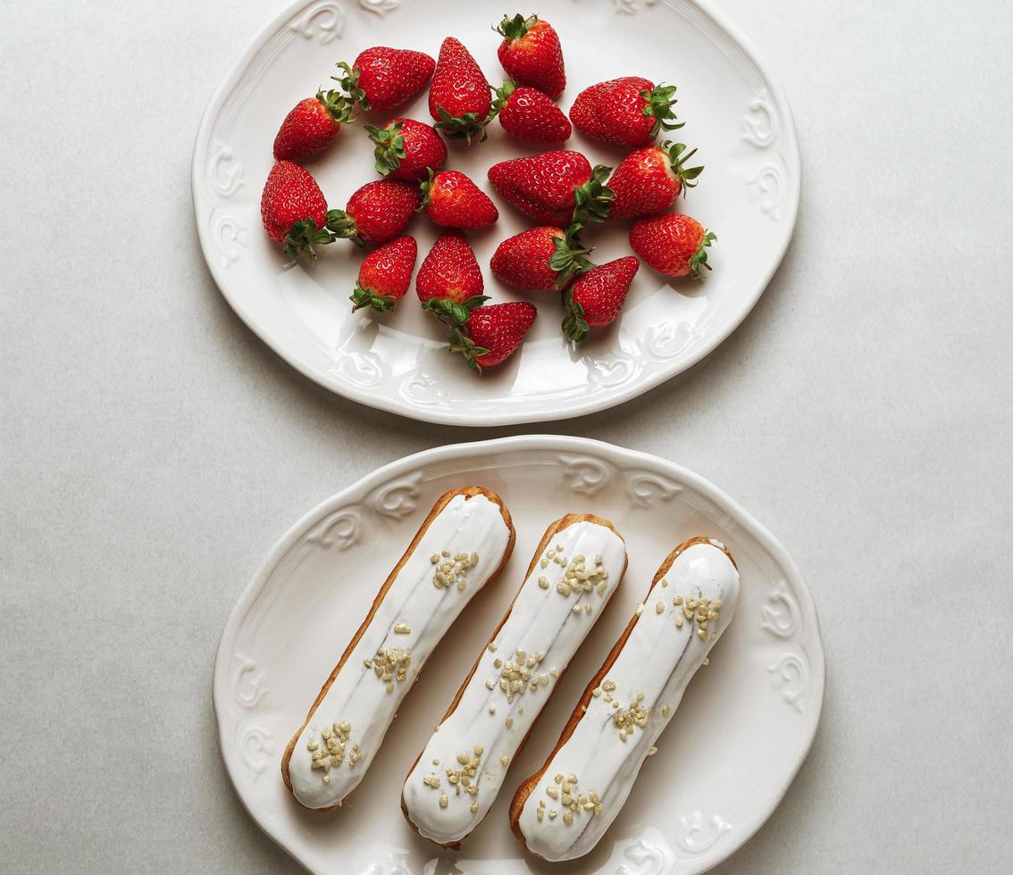 White glazed eclairs served with strawberries photo