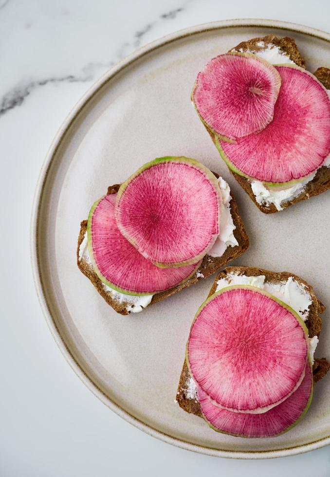 Watermelon radish and cream cheese sandwiches on rye bred on plate photo