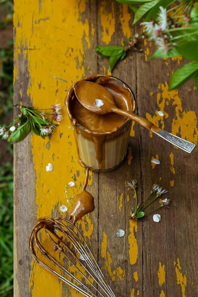 Korean dalgona coffee in a glass served on an old yellow garden table on a spring day photo