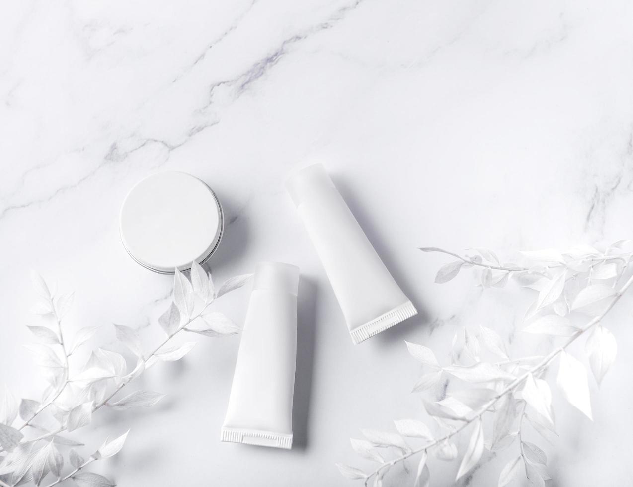 White tubes of cream on a marble background photo