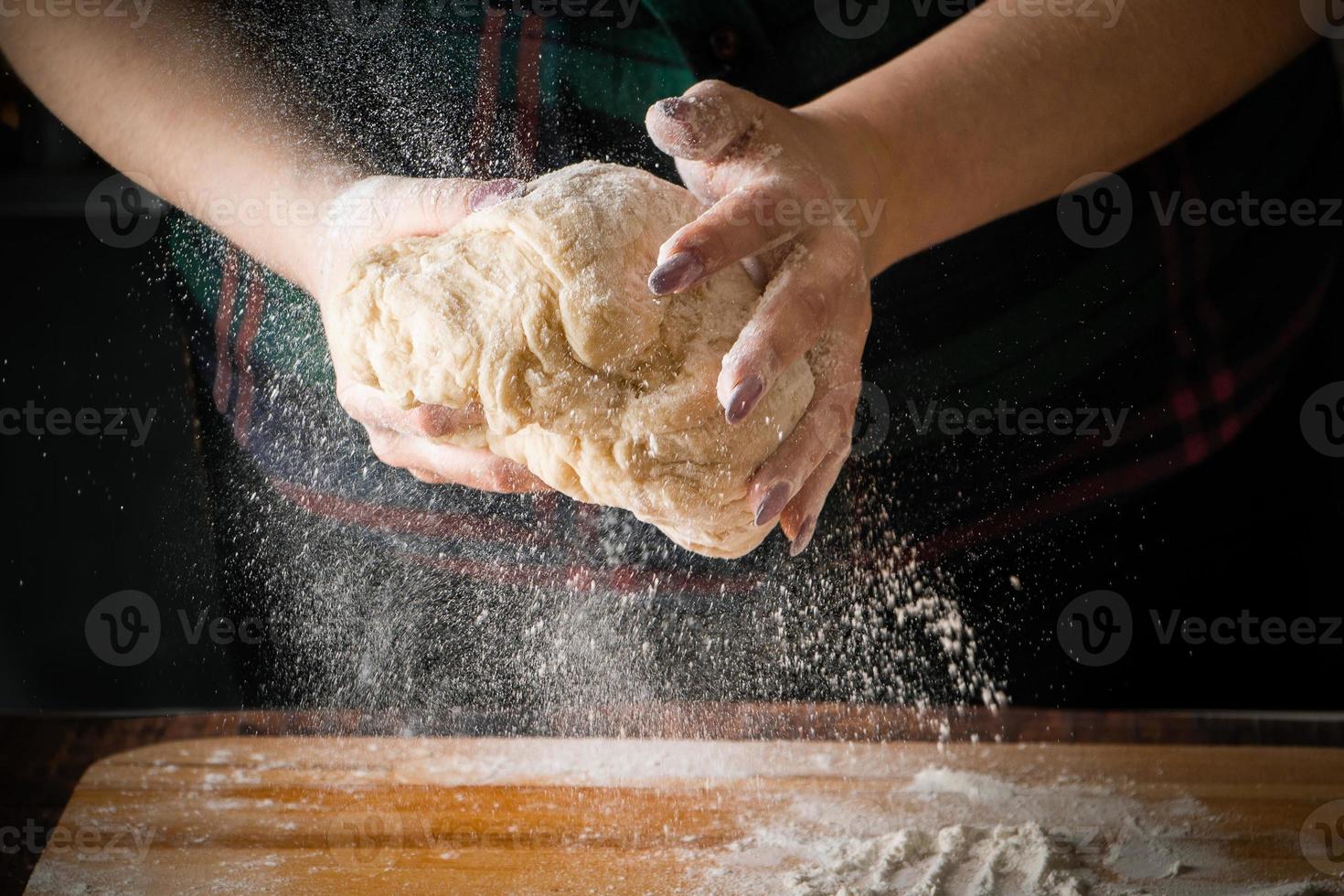 Chef kneads pizza dough on a board photo