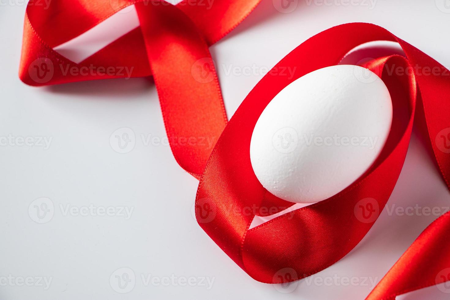 huevo blanco con cinta de seda roja foto