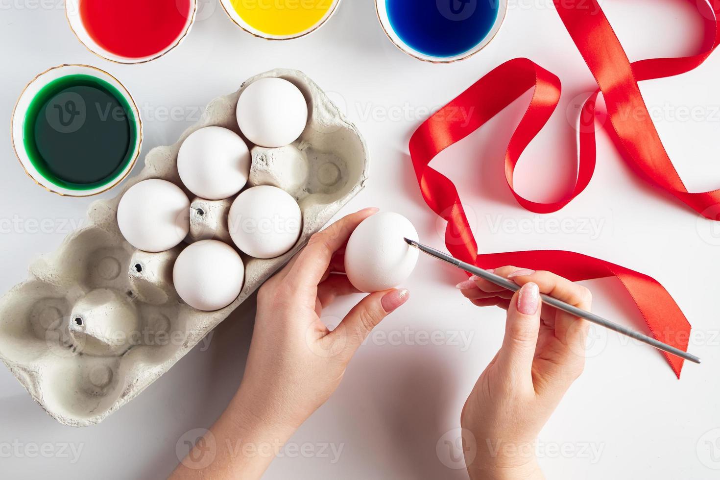 Young woman paints white eggs for easter photo