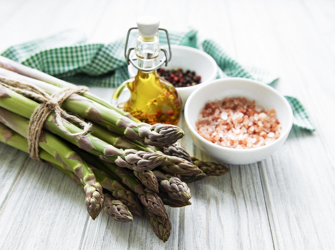 Bunch of raw asparagus stems with different spices photo