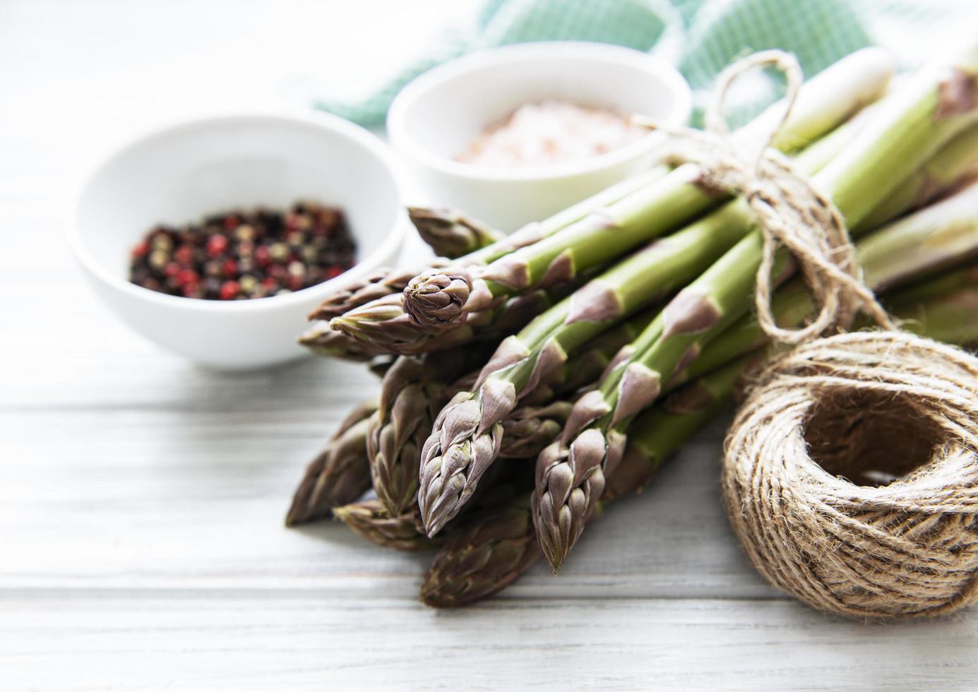 Bunch of raw asparagus stems with different spices photo