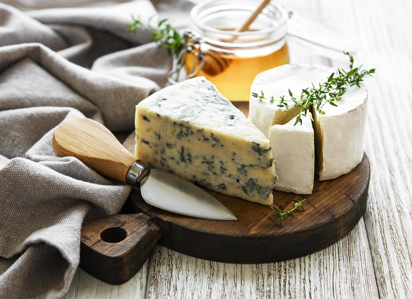 Various types of cheese, blue cheese, brie, camembert, and honey on a wooden table photo