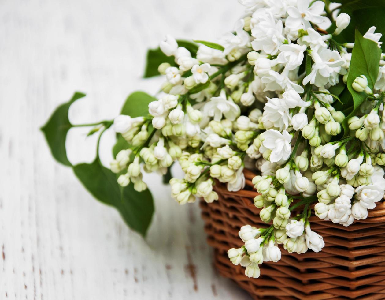 Cesta con flores lilas blancas sobre un fondo de madera foto