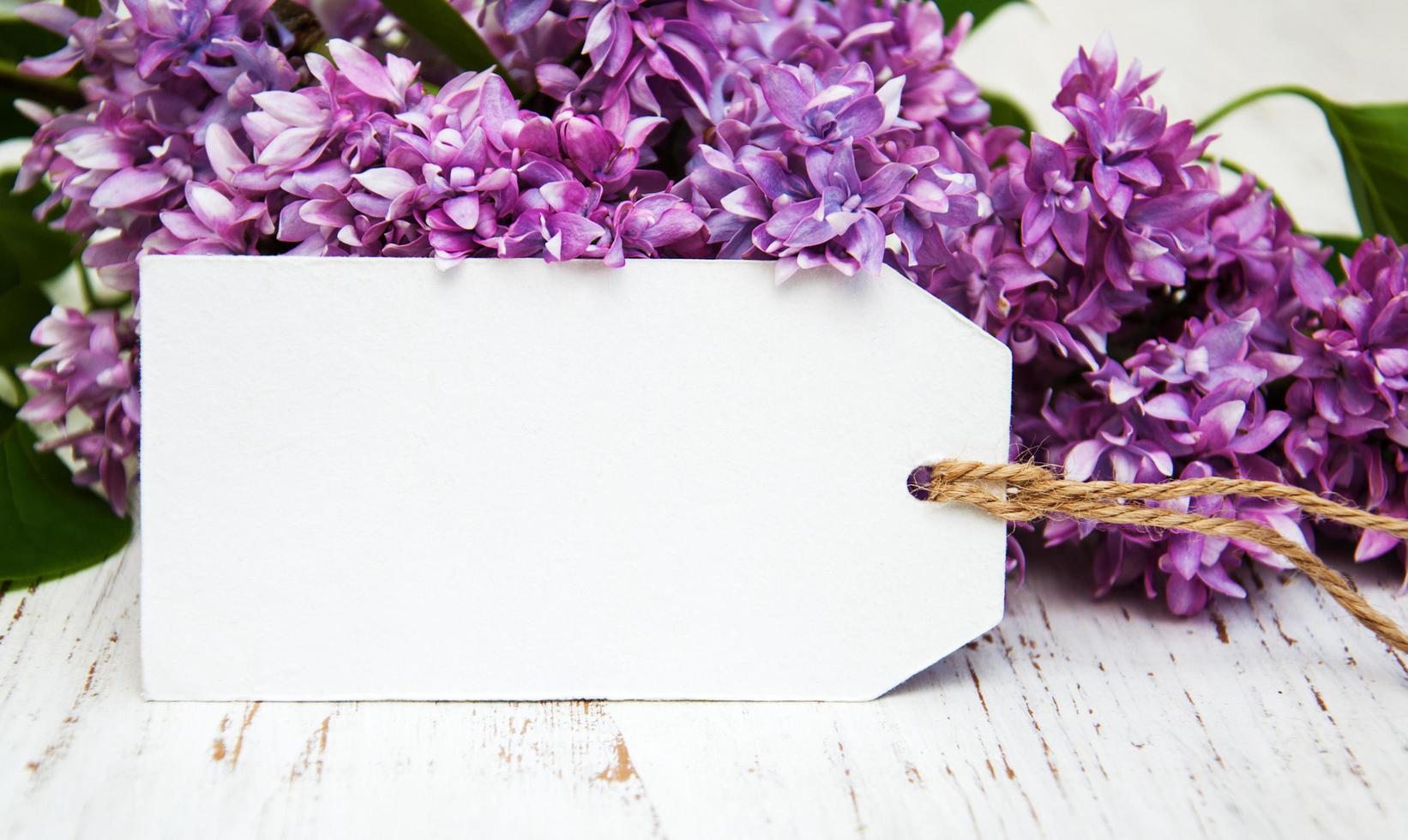 Lilac flowers with an empty tag on an old wooden background photo