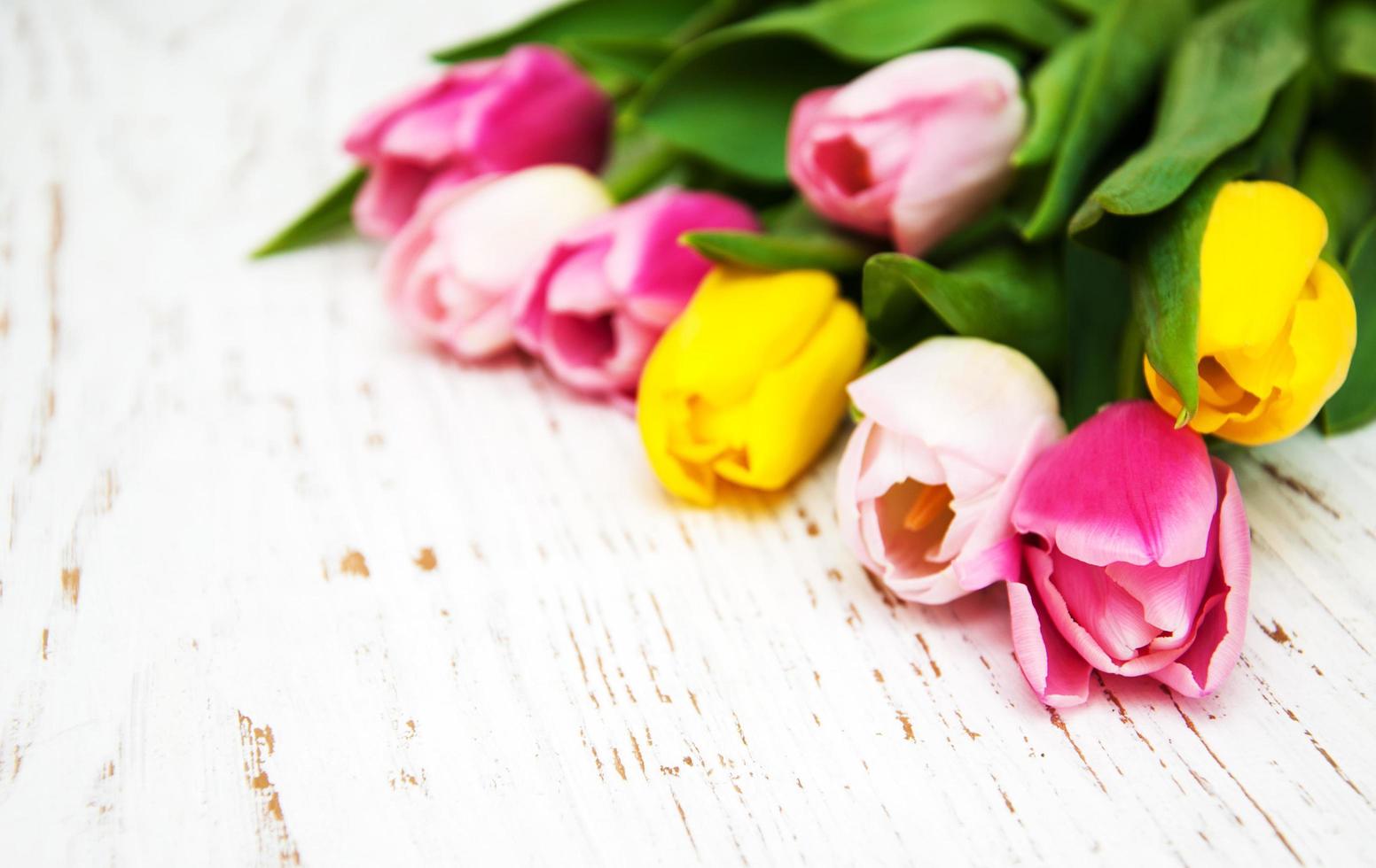 Ramo de tulipanes rosados y amarillos sobre un fondo de madera foto