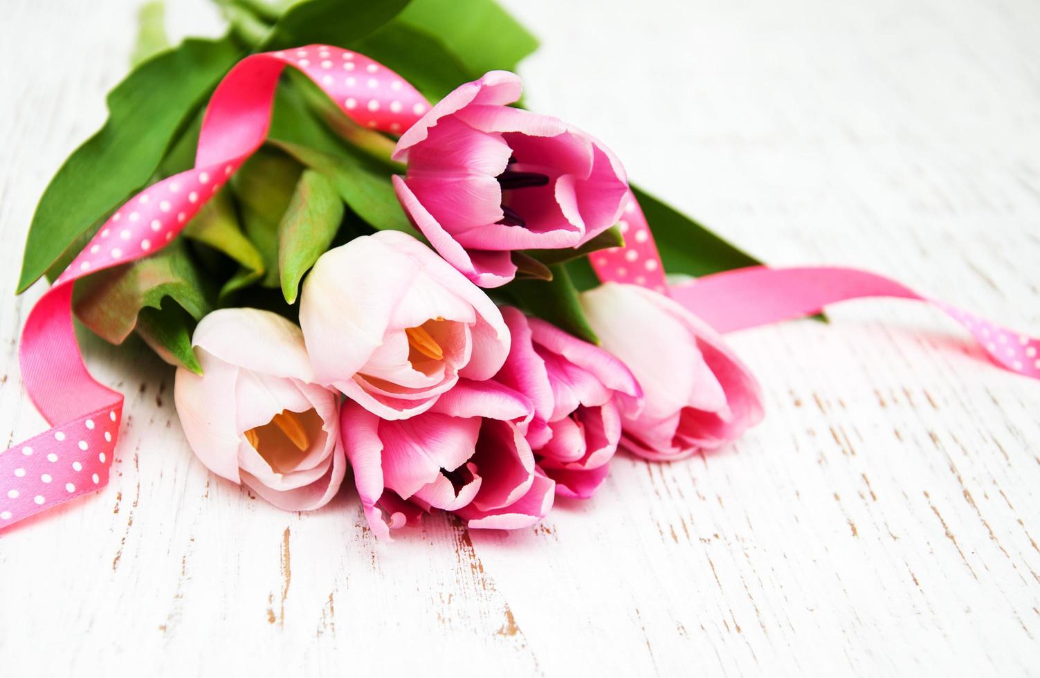 Ramo de tulipanes rosas sobre un fondo de madera vieja foto