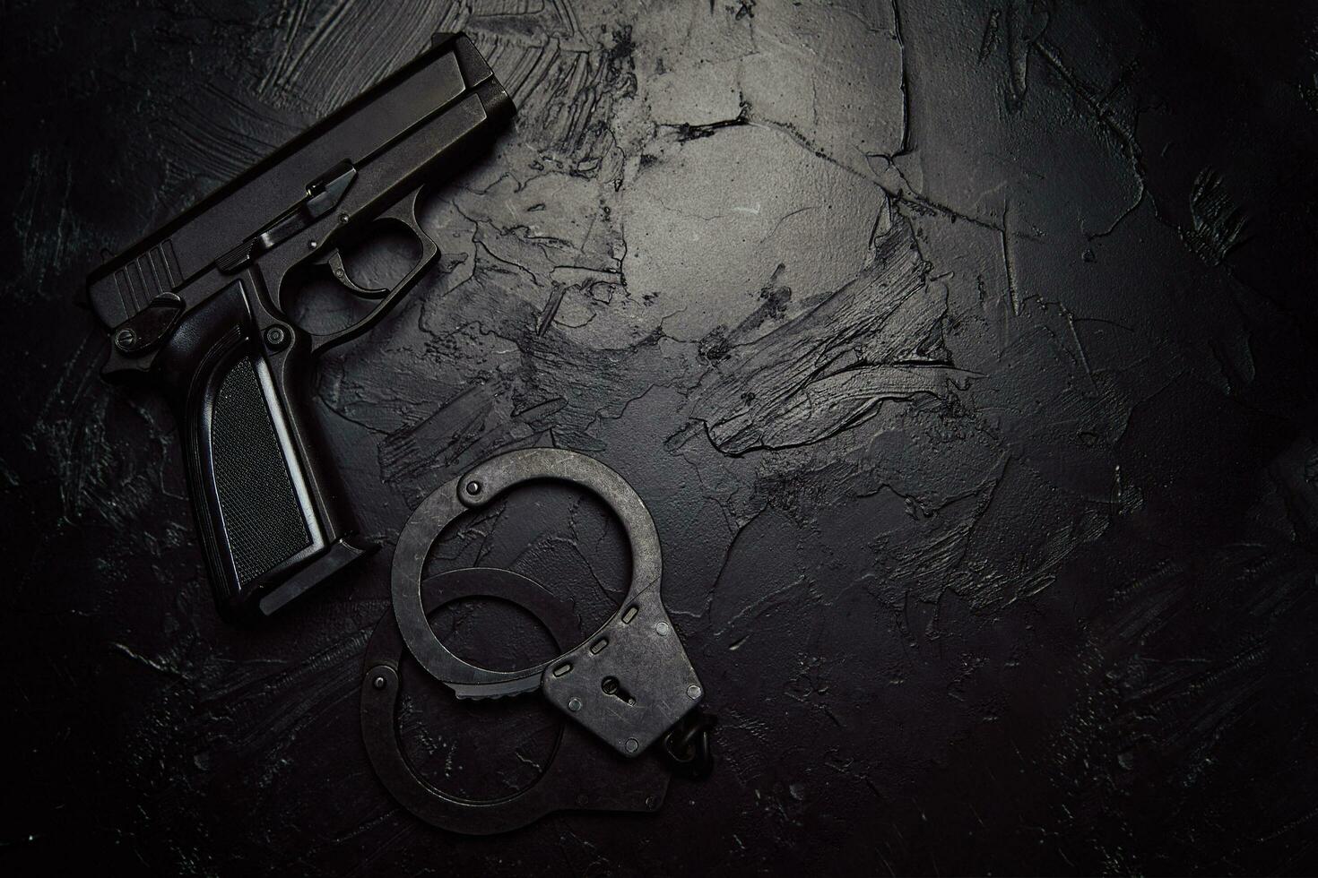 Gun and handcuffs on black textured table photo