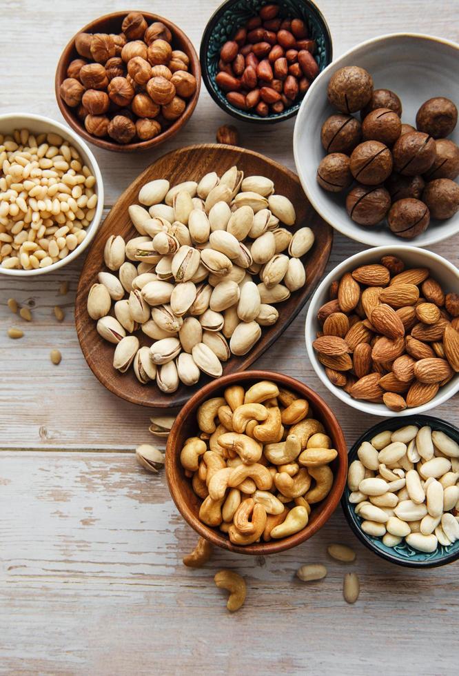 Bowls with various nuts on an old wooden background photo