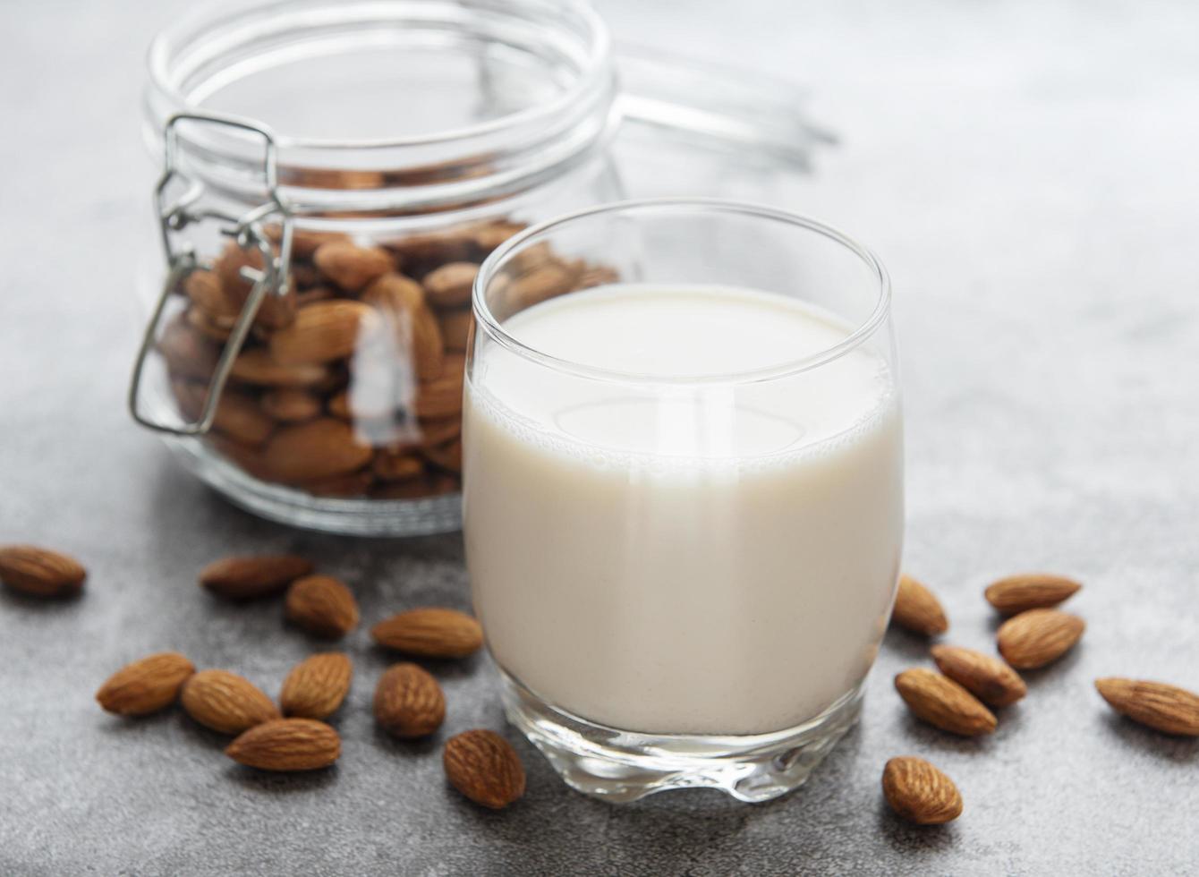 Glass bottle with almond milk and almonds on the table photo