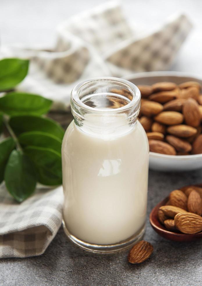 Glass bottle with almond milk and almonds on the table photo